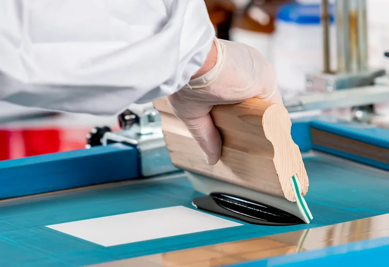 Gloved hand drawing down a coating film on a test chart in the DAAS laboratory